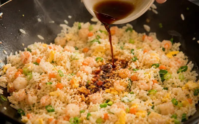 adding soy sauce to fried rice